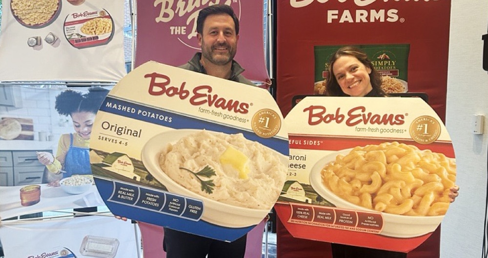 Oversized Bob Evans packaging mockups held by booth staff at tradeshow