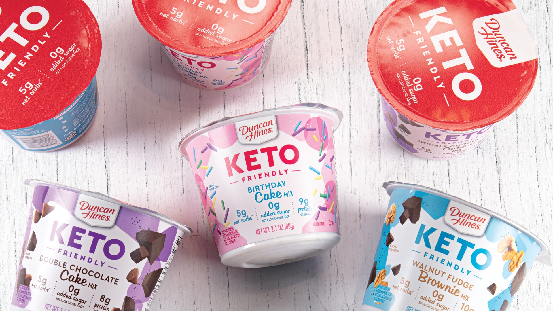 Duncan Hines Keto Friendly cake cup packaging design flatlay showing Birthday Cake Double Chocolate and Walnut Fudge Brownie flavors with red lid detail by Kaleidoscope